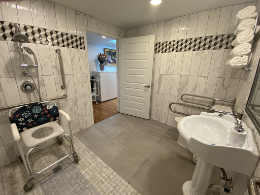 A spacious and accessible bathroom designed with safety in mind, featuring grab bars and a shower chair.
