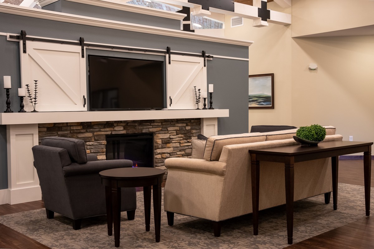 A modern living room with sofas, a fireplace, and a mounted television.