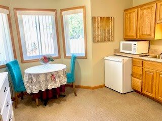 A cozy kitchen corner with a dining table, chairs, and appliances.