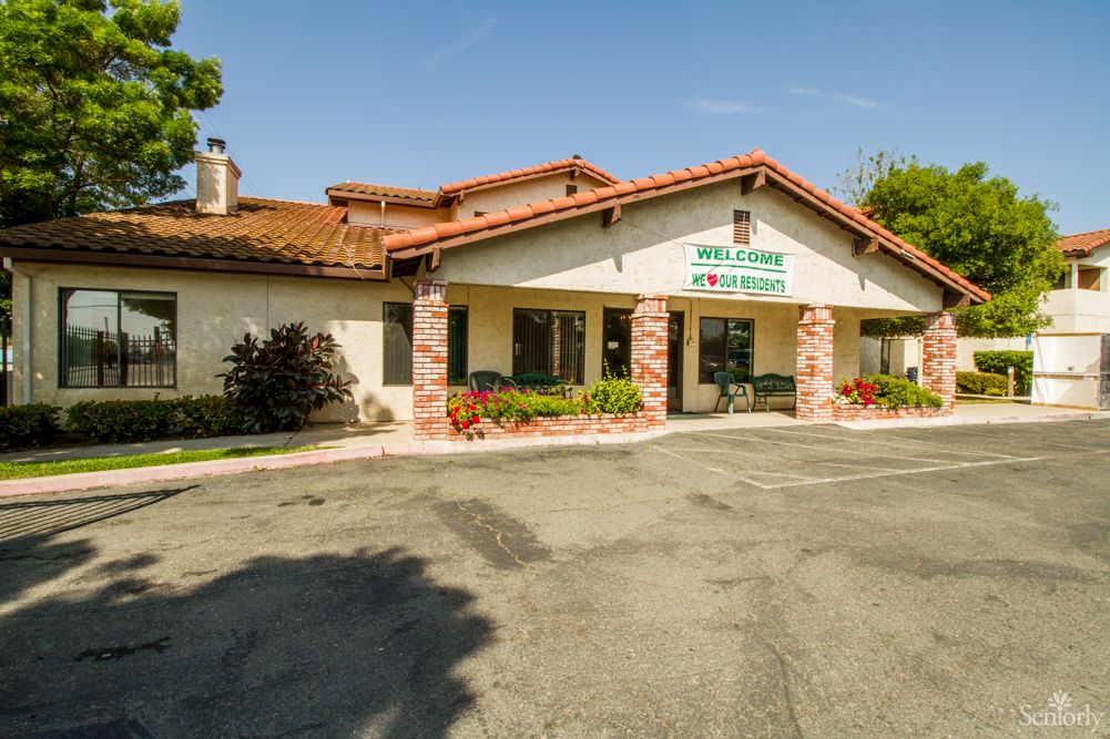 An exterior view of a clinic building with a parking area in front.