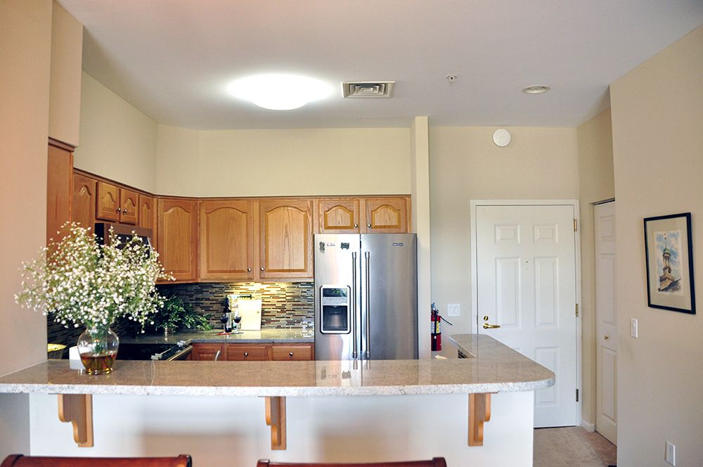 A modern kitchen with wooden cabinets and a sleek refrigerator.