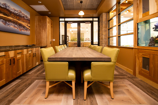 A modern dining room featuring a large wooden table surrounded by stylish yellow-green chairs, illuminated by natural light.