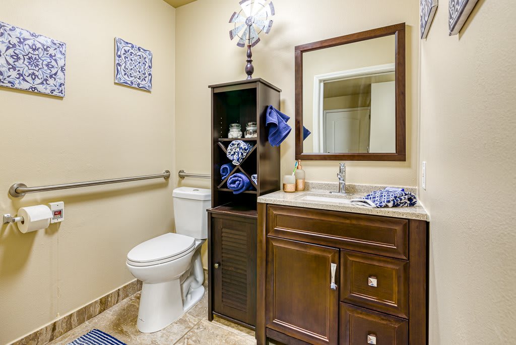 A modern bathroom featuring a toilet, sink with a mirror, and a storage cabinet.