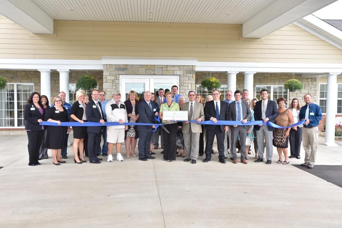 A group of people participating in a ribbon-cutting ceremony outside a building.