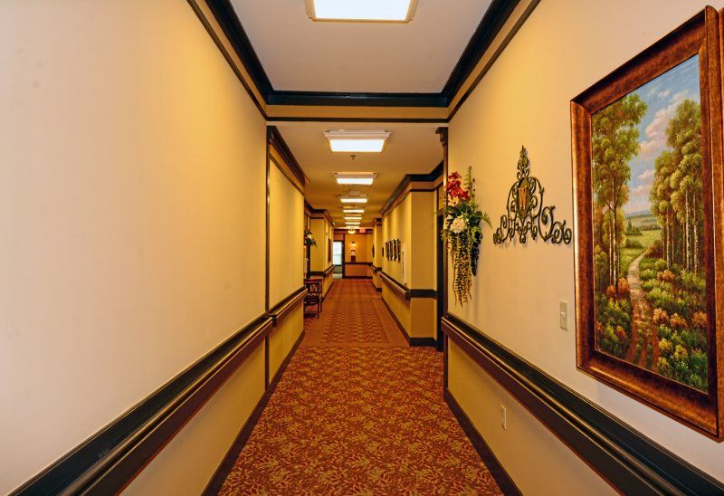 A well-lit hotel hallway with carpeted floors and decorative wall art.