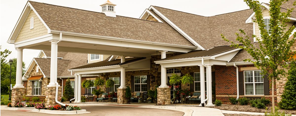 A welcoming entrance of a building with columns and surrounding greenery.