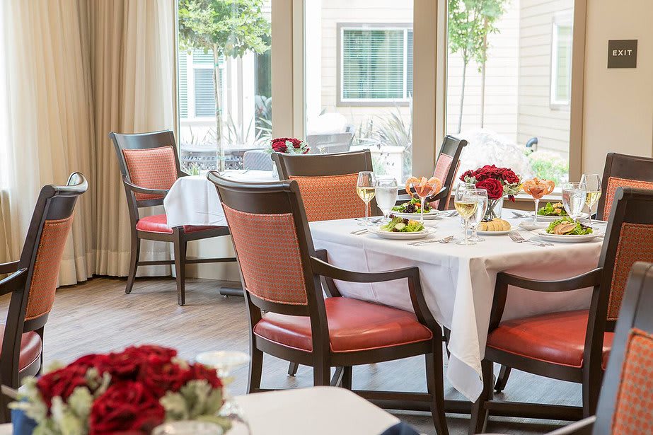 A well-set dining area with tables and chairs, adorned with flowers, ready for guests.