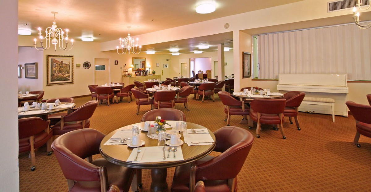 An inviting dining area with neatly arranged tables and chairs, featuring elegant place settings and soft lighting.