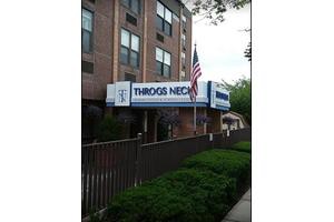 Entrance to a building with a 'Throgs Neck' sign and an American flag.