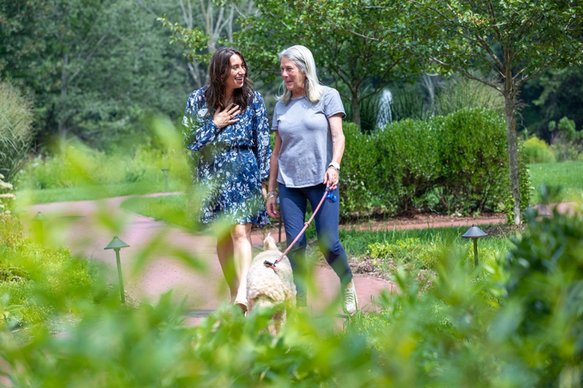 Two women walking a dog in a park, enjoying a conversation.