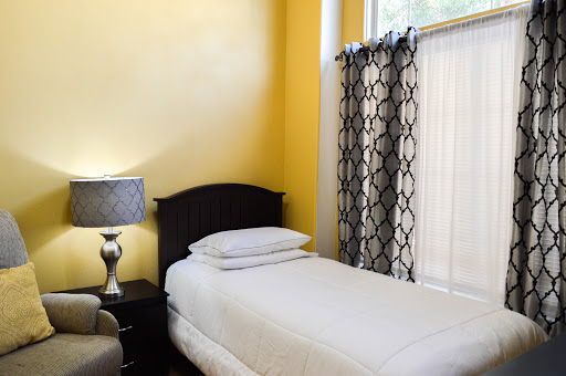 A cozy bedroom featuring a single bed, yellow walls, and stylish curtains.