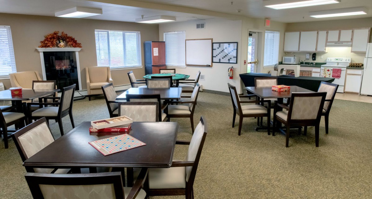 A community room with tables and chairs, featuring board games on the tables.