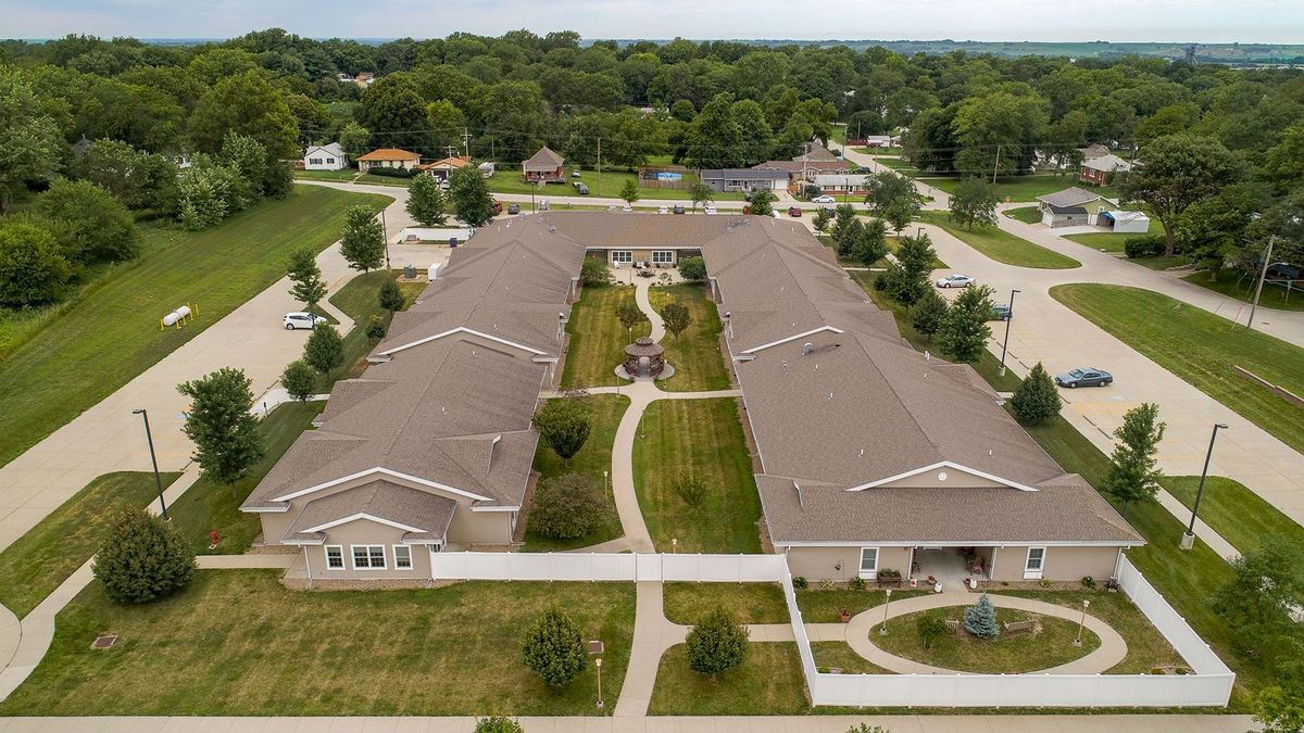 Aerial view of a residential complex with green pathways and surrounding suburban area.