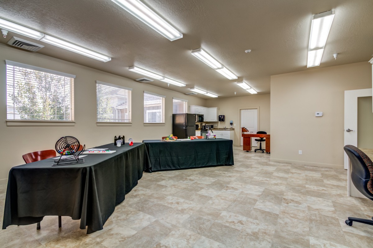 An empty conference room with tables and chairs under bright overhead lighting.