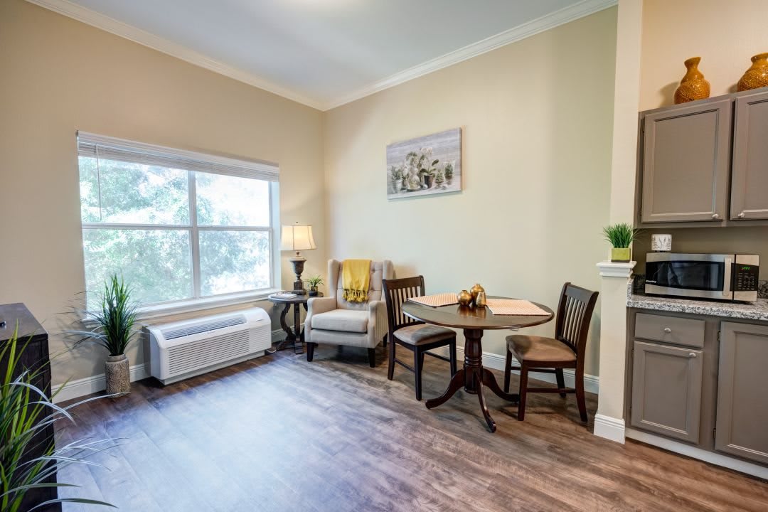 A cozy living room with a table, chairs, and a large window.