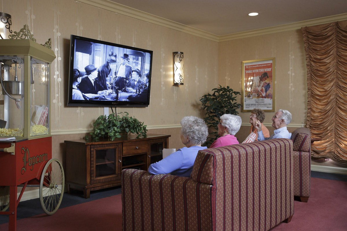 A group of seniors watching television in a comfortable living room setting.