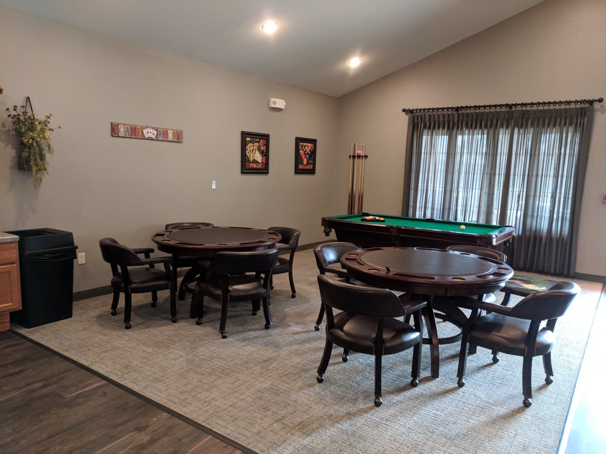 A game room featuring a pool table, round tables with chairs, and decor on the walls.
