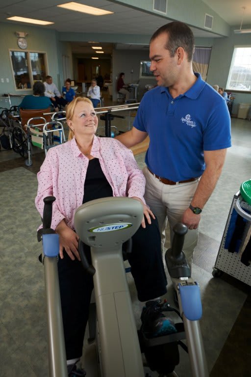 A patient using an exercise machine under the guidance of a healthcare professional.