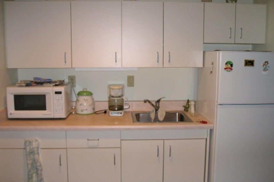 A kitchen with white cabinets, countertop appliances, and a sink.