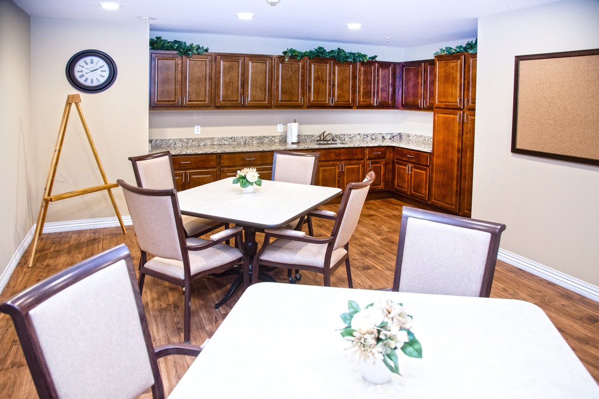 A well-lit dining area with wooden cabinets and floral centerpieces on the tables.