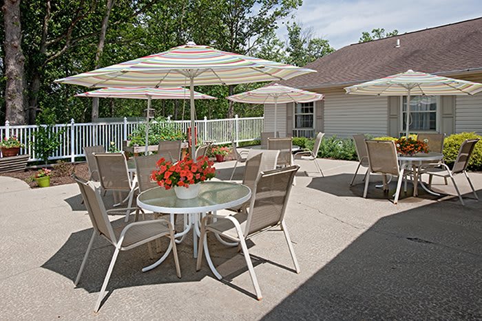 A sunny outdoor patio with tables, chairs, and umbrellas adorned with flowers.