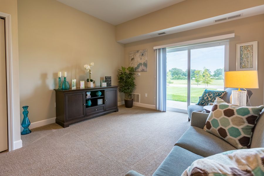 A modern living room with a sofa, TV stand, and sliding glass doors opening to a scenic view.