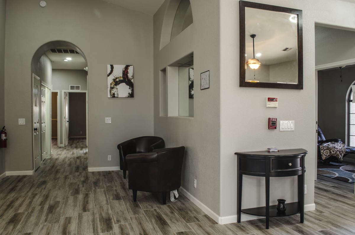 A modern waiting area with chairs, artwork, and a mirror on the wall.