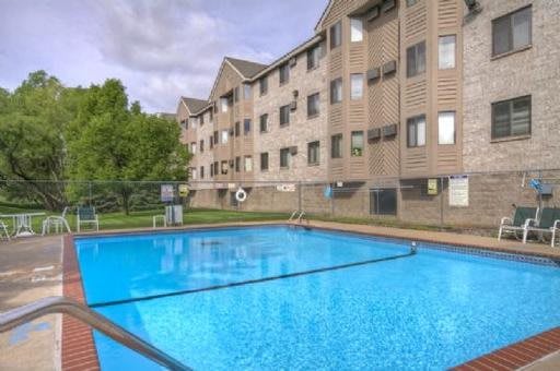 An outdoor swimming pool next to a multi-story apartment building on a clear day.