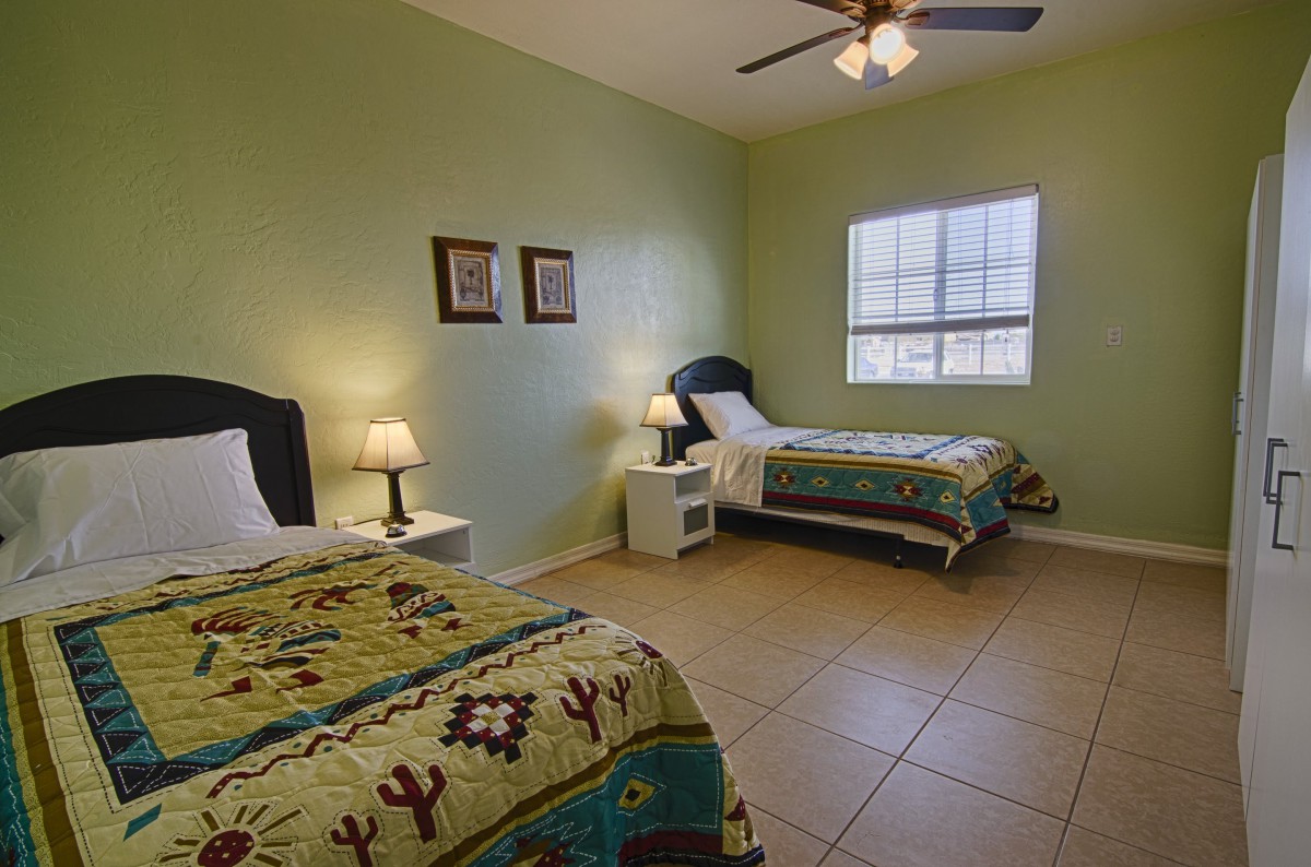 A cozy bedroom with two single beds, complemented by green walls and warm lighting.
