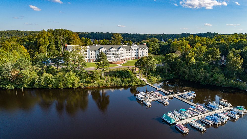 A scenic view of a lakeside hotel with a marina surrounded by lush greenery.