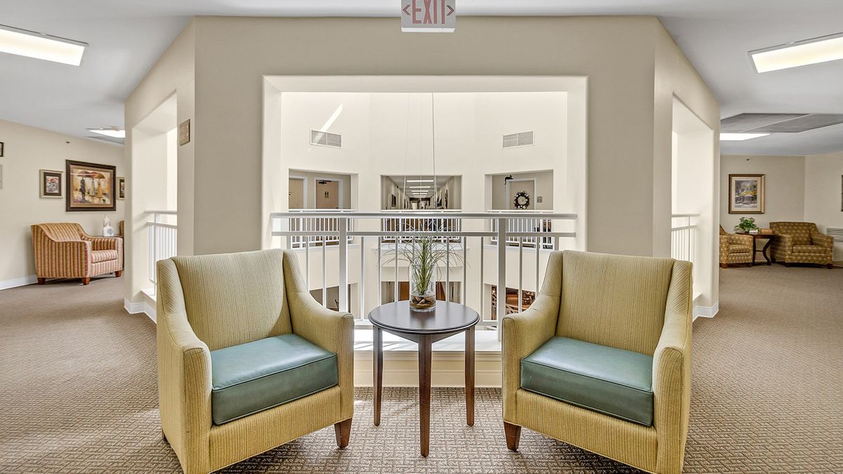 A cozy lounge area featuring two chairs and a small table with a plant centerpiece.