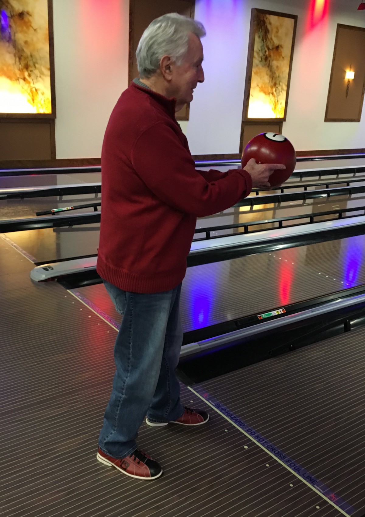 A man preparing to bowl at an indoor bowling alley.