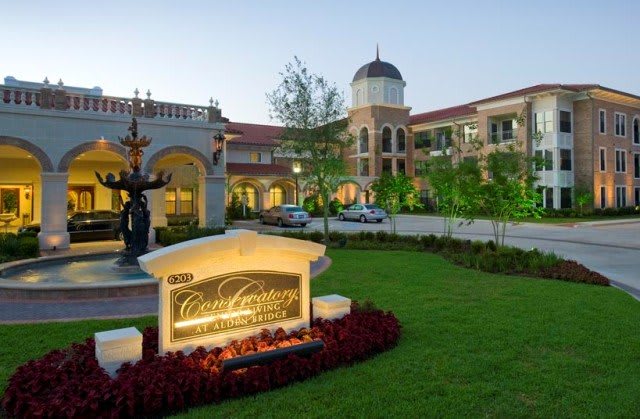 A beautifully lit building with a dome, statues, and landscaped gardens at dusk.