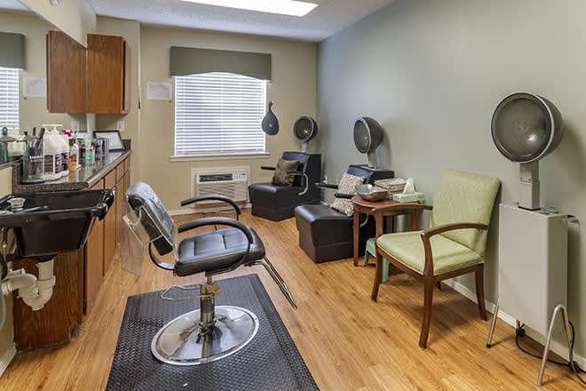 A cozy salon interior with a barber chair, hair dryers, and a waiting area.