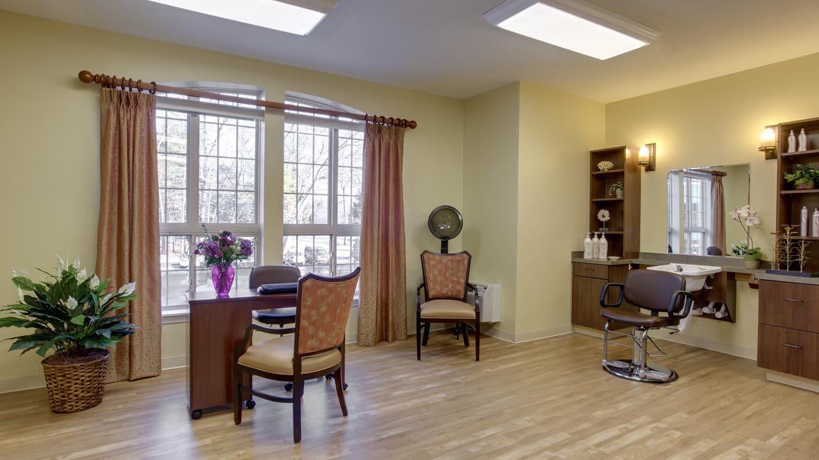 A cozy waiting room with chairs, a table, and a window with curtains.