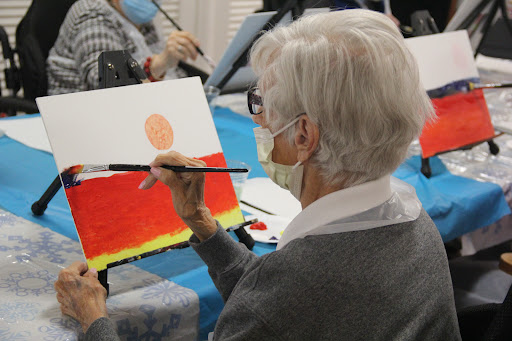 An elderly individual engages in a painting session, showcasing creativity and artistic expression.