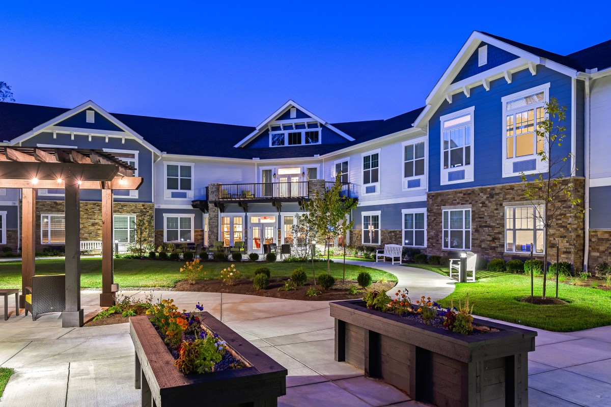 A modern residential building with a landscaped courtyard at dusk.