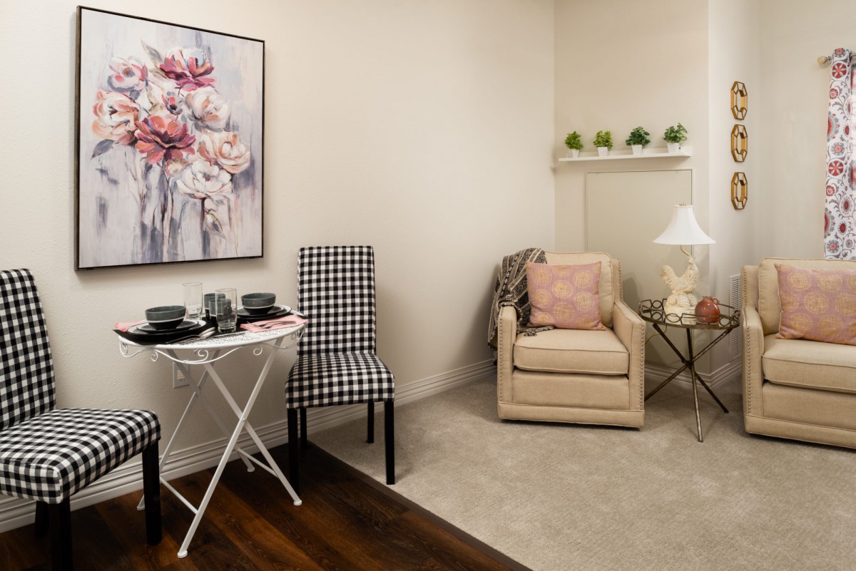 A cozy living room corner with a comfortable chair, decorative artwork, and stylish furnishings.
