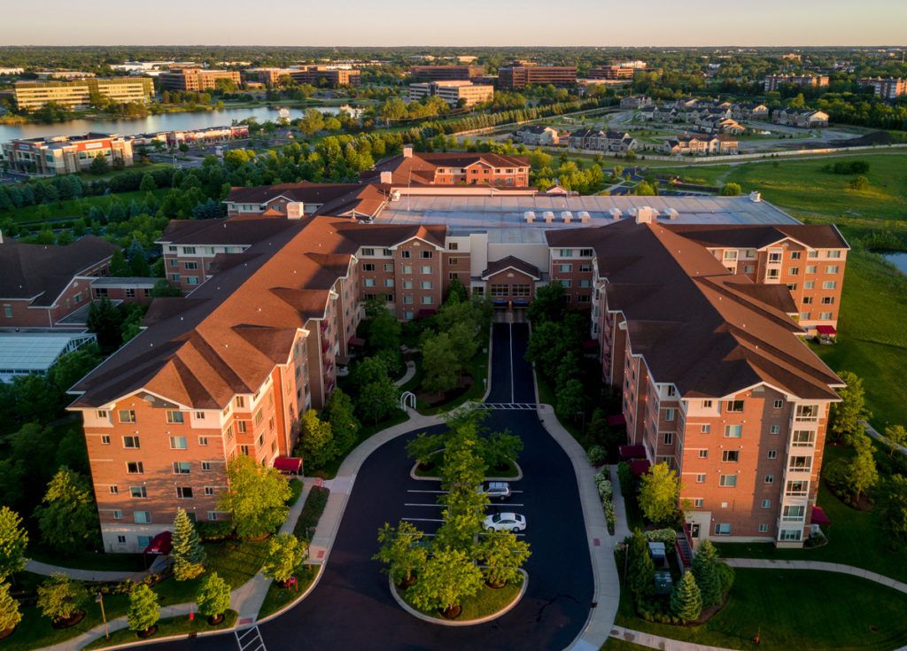 Aerial view of a housing complex surrounded by greenery and roads.