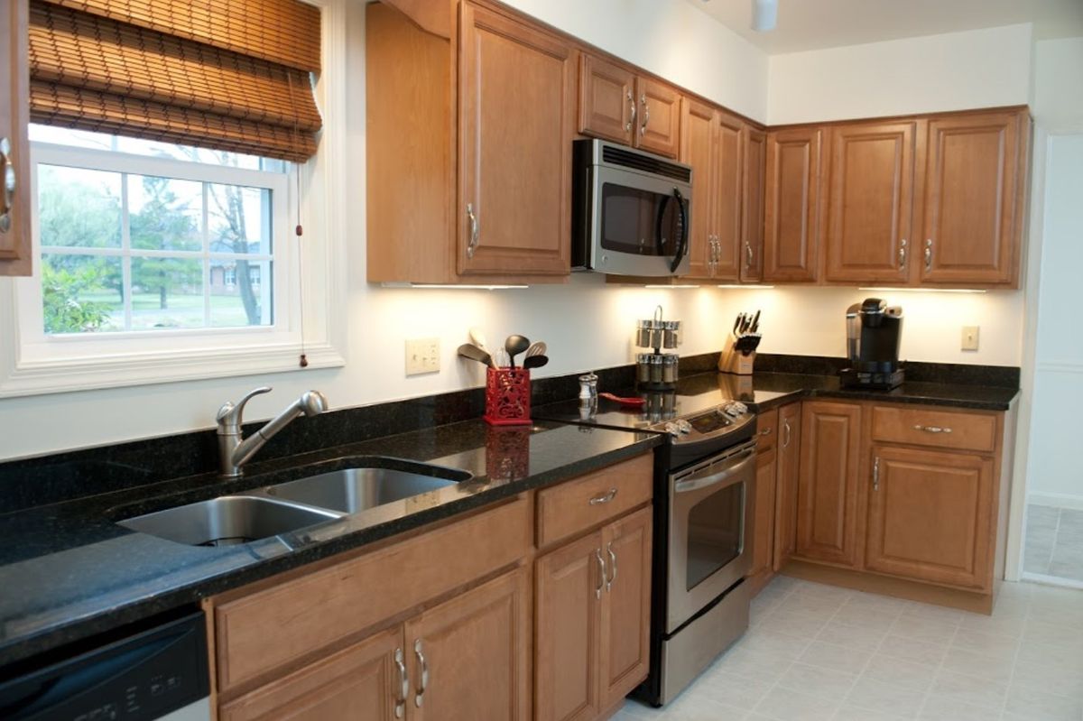 A modern kitchen with wooden cabinets, stainless steel appliances, and a double sink.