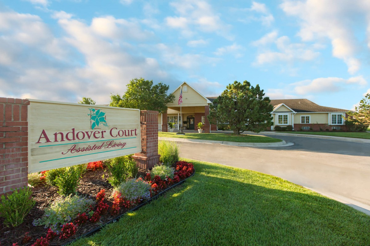 A welcoming entrance with a landscaped garden and a sign for Andover Court, set against a cloudy sky.