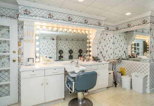 A well-organized vanity space featuring a large illuminated mirror and a stylish blue chair, perfect for hair and makeup.
