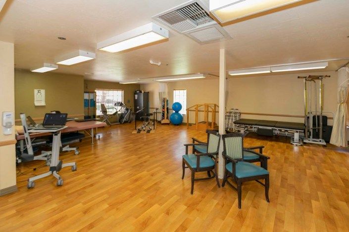 A well-equipped gym with exercise machines and a wooden floor.