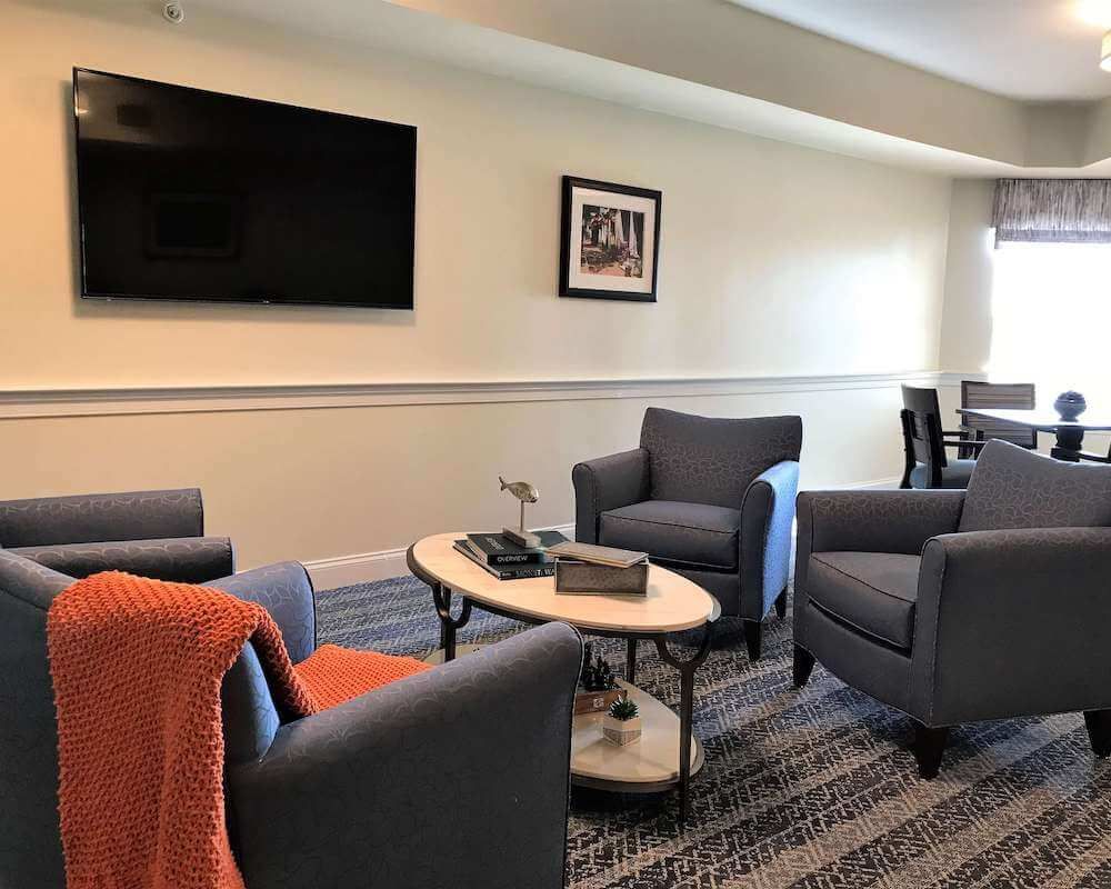 A cozy living room with armchairs and a coffee table facing a wall-mounted television.