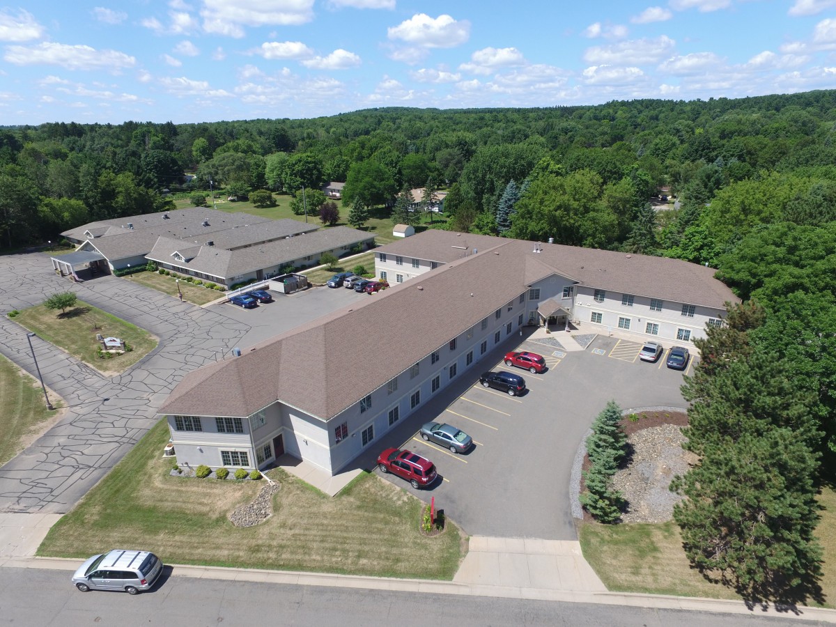 Aerial view of an apartment complex with a parking lot and surrounding greenery.