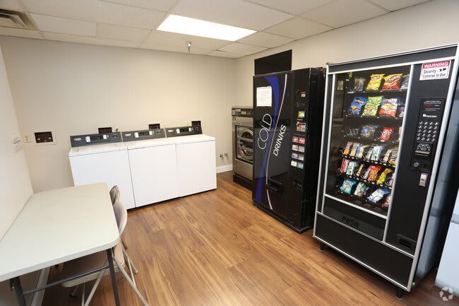 A laundry room equipped with vending machines, washers, and seating area.