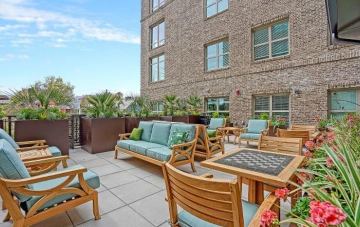 A cozy patio area with wooden furniture and lush greenery in an urban setting.