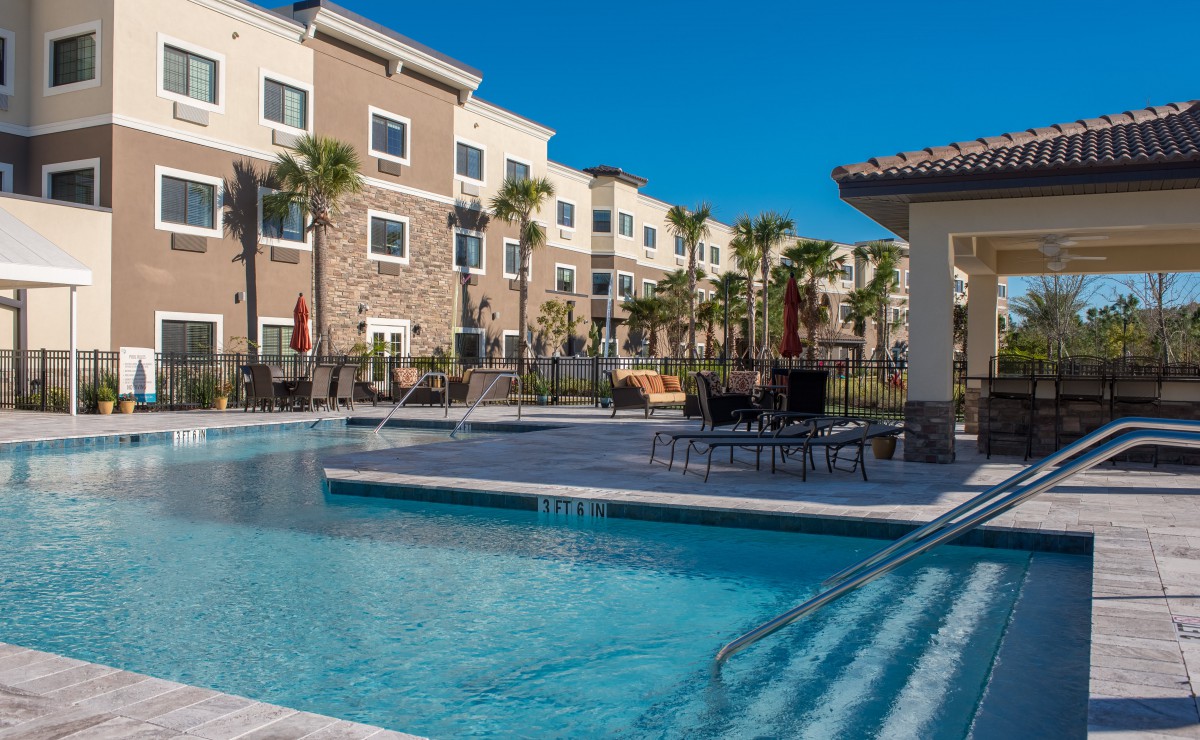 A sunny day at an apartment complex with a swimming pool and palm trees.