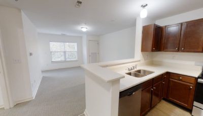 A modern apartment interior featuring an open kitchen with a view into the living room.
