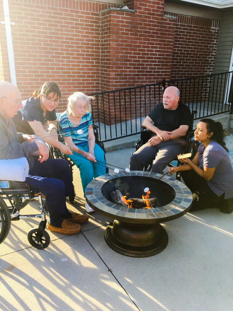 A group of people sitting around a fire pit, enjoying a casual outdoor gathering.